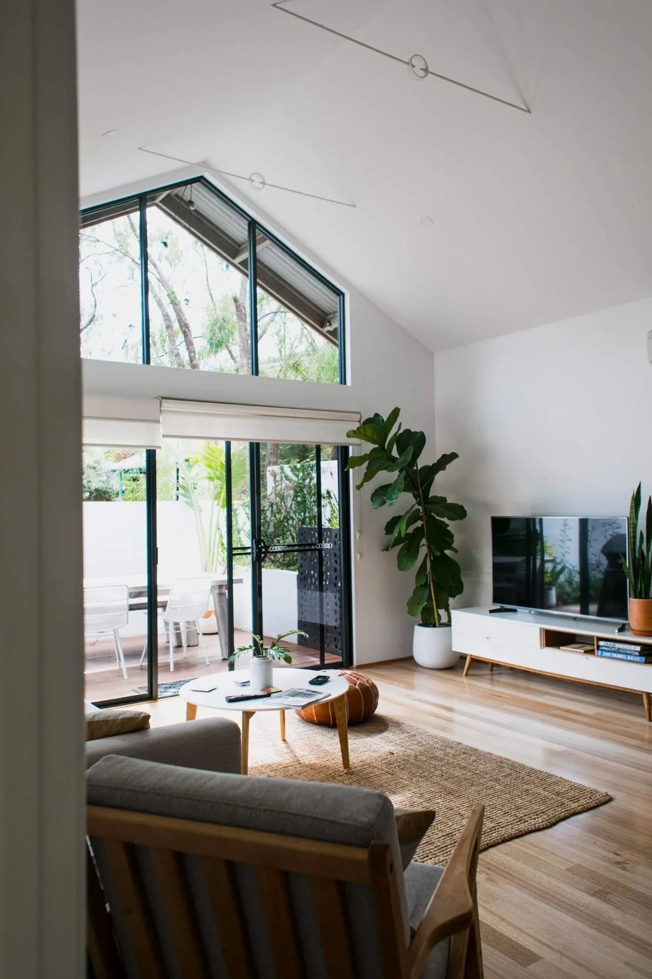 Bright open-plan living room with polished timber floors and tall windows
